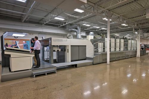 men standing at printing press in plant